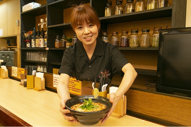 店長の綱島綾子さん。｢辛くないスパイスラーメンです。辛いのがお好みの方には｢辛さ増し｣(＋30円)もあります。1辛から5辛まで選べます｣