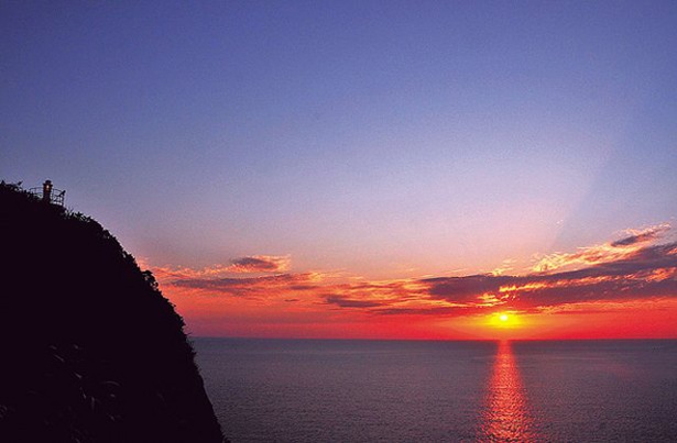 【画像を見る】東シナ海に沈む夕日が、ドラマチックに空と海をオレンジに染め上げるさまは必見 / 十三仏公園展望所