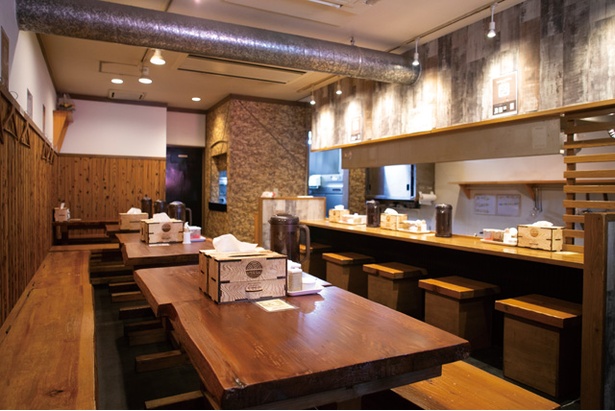 カウンター、テーブル共に木目調。入口横に製麺機が置いてある / とんこつらぁめん いちむじん