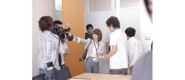 メイキングシーンより。名刺をカメラに向けて嬉しそうな大島さん