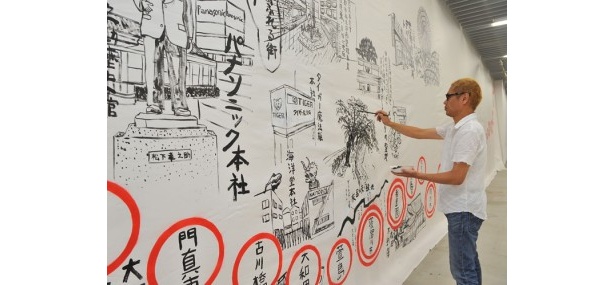 巨大絵図「京阪沿線御案内」（部分）2011の制作風景。西野「各駅の絵やコメントは、現地で撮影した写真などを見て、下書きなしで描いています」