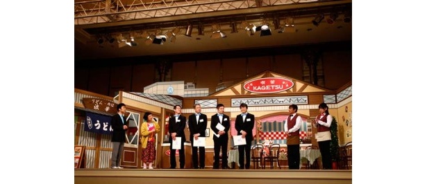 吉本新喜劇の舞台に登場する内場勝則、未知やすえ、藤井隆、すっちー。蝶ネクタイ姿の吉本社員はプロジェクト概要を練習という態でプレゼン
