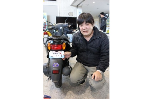 「1」番のプレートとともにはにかむ佐久川さん