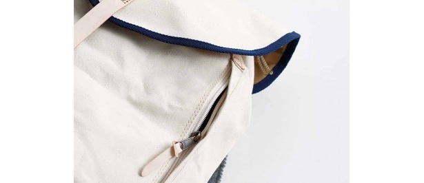 リュックのサイドにはファスナーを付け、フラップのベルトを外さずに荷物が出し入れできる。