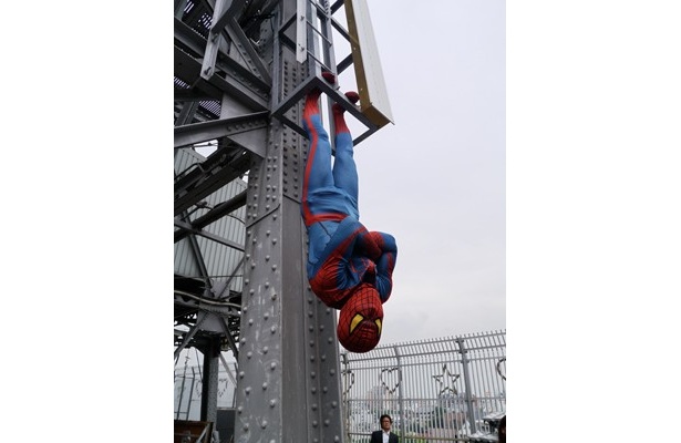 通天閣の鉄柱に、足だけで宙釣り状態になってみせるスパイダーマン