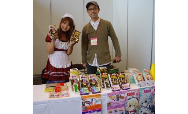 秋葉原UDXでも個数限定で物販販売している。右はケーキ製造元の高橋さん。「色はキツいけど味と品質は保証します」