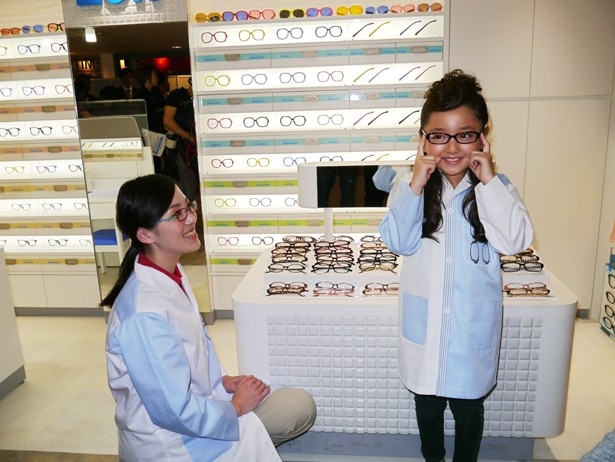 店頭に様々並んだメガネを実際に手にとって合わせる花音ちゃん