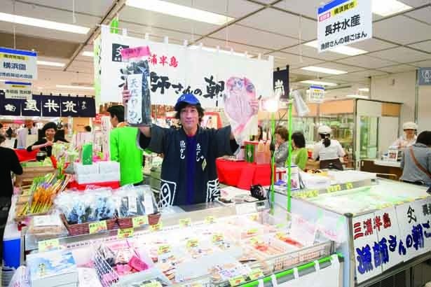 「天然わかめ」（200g・1200円）、「特大金目鯛干物　天日干し」（2500円）を手に声をかける高田寛之さん/長井水産
