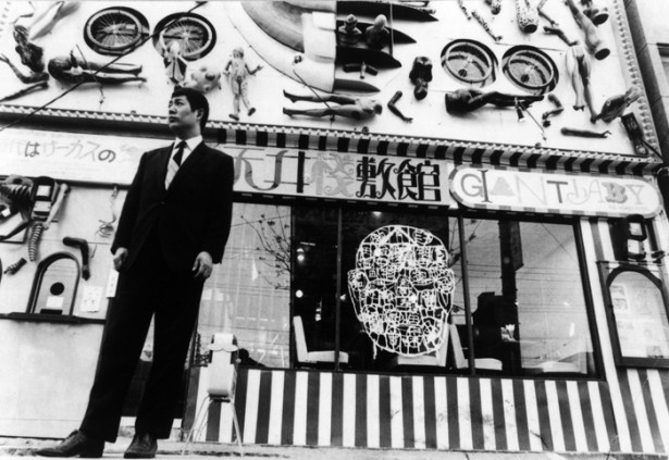 【写真を見る】寺山修司。渋谷に落成した天井棧敷館の前で(1969 年)