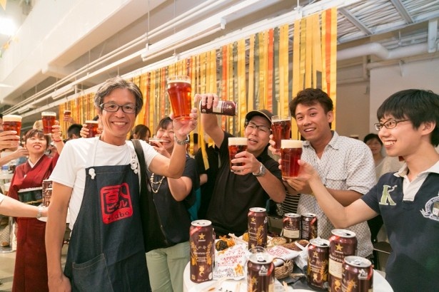 商品をコップに入れ乾杯をするイベント参加者とスタッフ