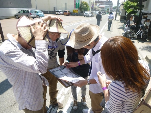 暗号だらけの地図に記された宝物のありかに向かうため、町中を歩き回る参加者