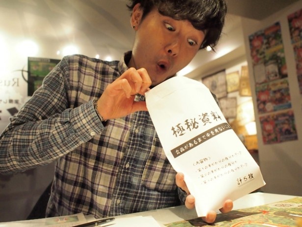 暗号解読に行き詰まり、差し出された極秘資料に飛びつく記者。おバカでもある程度は先に進められるのがうれしい…