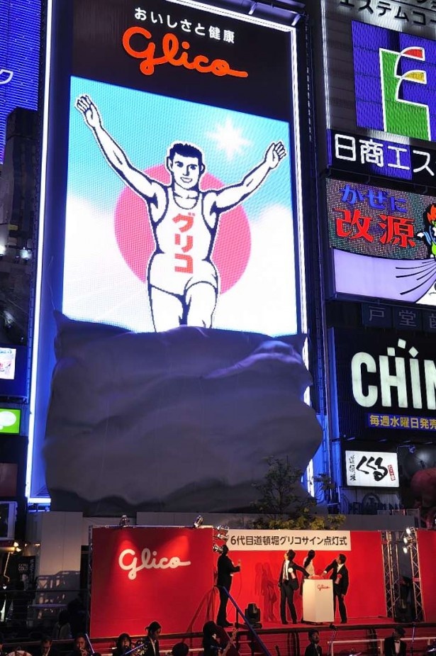 カウントダウンと共に点灯スイッチが押されると、サインを覆っていた幕が落とされ、6代目グリコサインが披露された