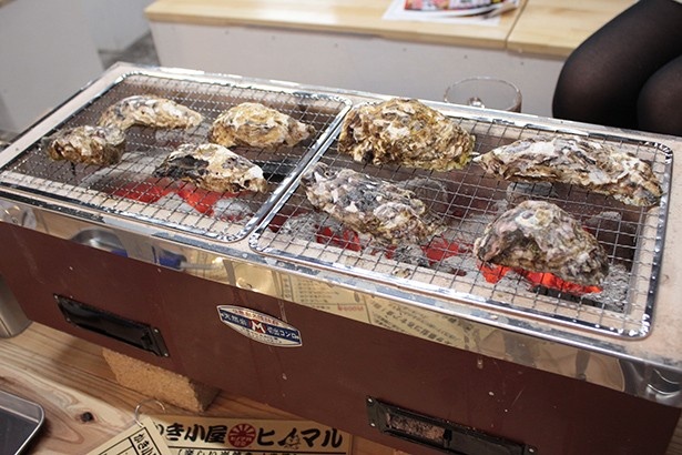 炭火焼きの網いっぱいにカキを並べて焼いていく