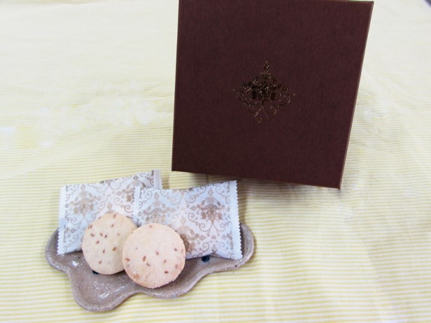 「金胡麻ちんすこう」(1500円・税別、16個入り)のパッケージは茶色。今までのちんすこうのイメージを覆すような、琉球豚のアグーやヤンバルクイナをモチーフにした装いが美しい