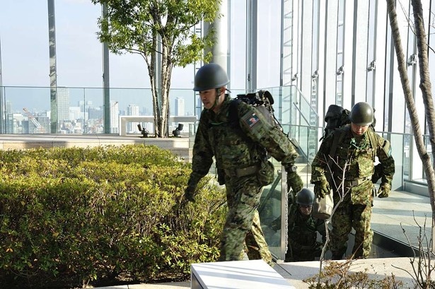 階段を上り16階庭園に入る通信小隊。6名のチームで活動する。背負っている背のうは約20キロの重さ