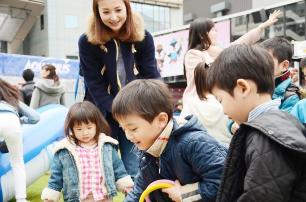 【写真を見る】輪投げで遊ぶ子どもたちを見守る美人ママ！「ビルに囲まれた空間でこうやって遊べるのはうれしいですね」