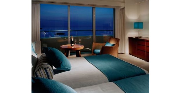客船をイメージした白×ブルーの客室。窓からは万座の海が一望できる
