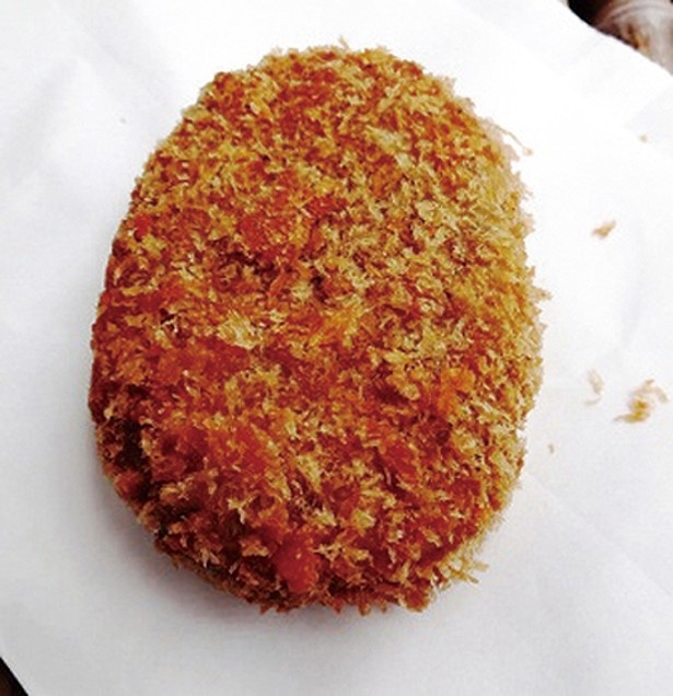 食べ歩きにピッタリな「吉田家」の名物「吉田家コロッケ」（85円）。ホクホクのジャガイモとあふれる肉汁が絶品