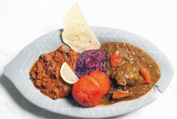 森林食堂の「長期成熟鶏のチキンほうれん草カレーと猪カレーの合がけ(焼トマトのトッピング付)」(1550円)。マンガ発売後、急激にオーダーが増えたという