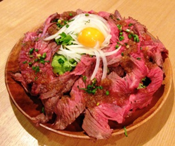 【写真を見る】「名物肉バルのTKG（ドゥミドゥミ）」(200g・1200円)は炭火焼にしたラム肉と牛肉が器からこぼれ落ちそうなほどのボリューム