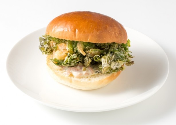 滋賀県の代表料理「日野菜のサラダソースで食べる 愛彩菜のかき揚げバーガー」。愛彩菜(わさび菜)のかき揚げを挟んだバーガー。ソースには日野菜漬けとわさびを加えた