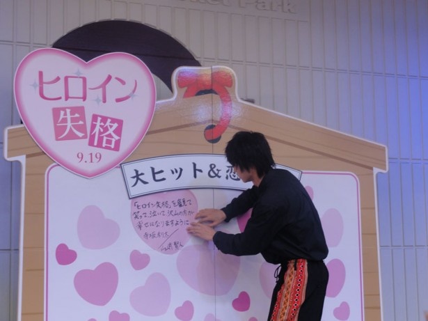 特大絵馬にトップバッターでメッセージを貼る山崎さん