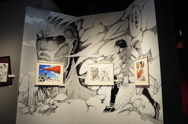 物語を象徴するようなシーンを背景に、原画が展示されている