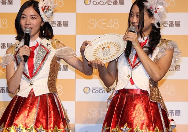 オリジナルカレー皿をアピールする松井珠理奈(写真左)と古畑奈和(同右)