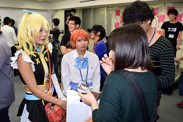 【写真を見る】名刺を交換しつつ、真剣な表情で話すコスプレイヤーたち