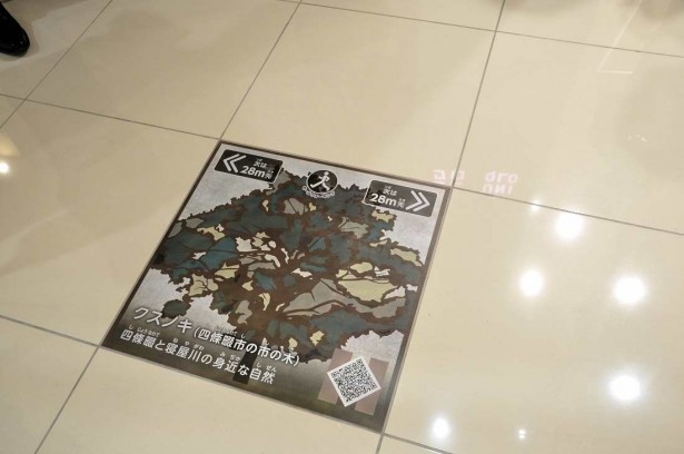 モールの床には四条畷市と寝屋川市の自然を題材にした表示が設置されている。スマホでQRコードを読み取ると、ウォーキングの記録も
