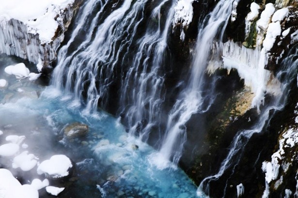 【写真を見る】白ひげの滝の辺りから流れ出る水と美瑛川の水が交わることによって、人の目には青く映る水となるそう。日中に白ひげの滝を見下ろすと、その分かれ目がはっきりとわかる