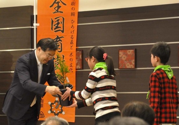 京都府の山田啓二知事やモデルフォレスト運動参画企業の担当者から緑の少年団に北山杉やしだれ桜など8本の苗木が引き渡された