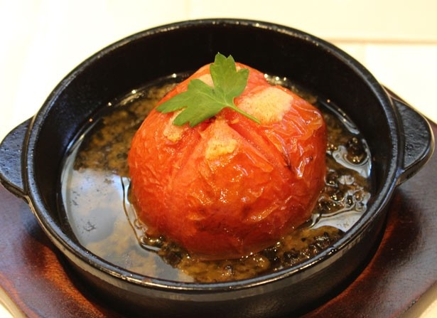 トマトを黒オリーブとアンチョビのソースで焼き上げた「まるごとトマトのタプナードソース バゲットつき」(750円)。見た目のインパクトも抜群！