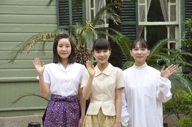 「萌黄の館」を背に、記念撮影に応える出演者。左から連佛美沙子、芳根京子、谷村美月