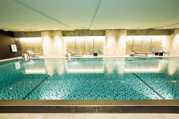 【写真を見る】プールは20m×3コース、水深1.15mで温水ジャクジーも完備。水の反射が美しいタイル敷きで、落ち着いた雰囲気だ