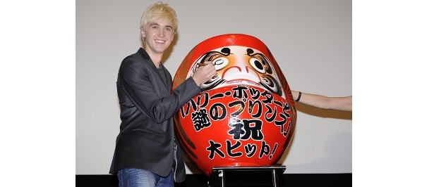 “大ヒット御礼”だるまに目を入れるドラコ役のトム・フェルトン
