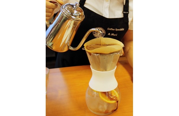 氷とオレンジスライスを入れたコーヒーメーカーに、ハンドドリップでコーヒーを注いでいく