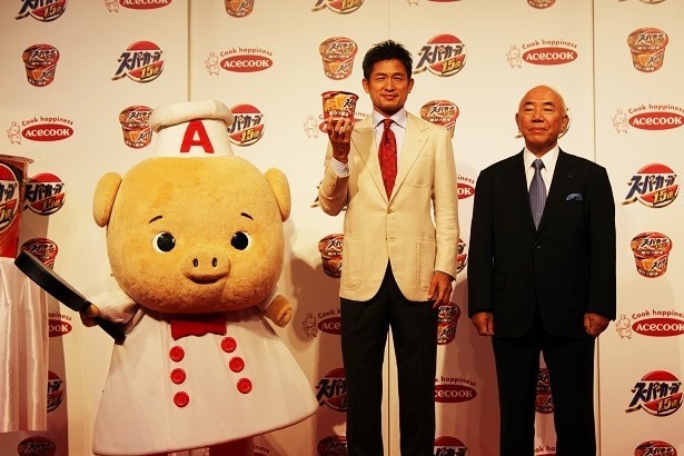 エースコック株式会社の村岡寛社長(右)、同社のキャラクターである「こぶた」(左)とのフォトセッション