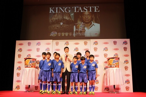【写真を見る】「KING TASTE」をバックにした三浦知良さん