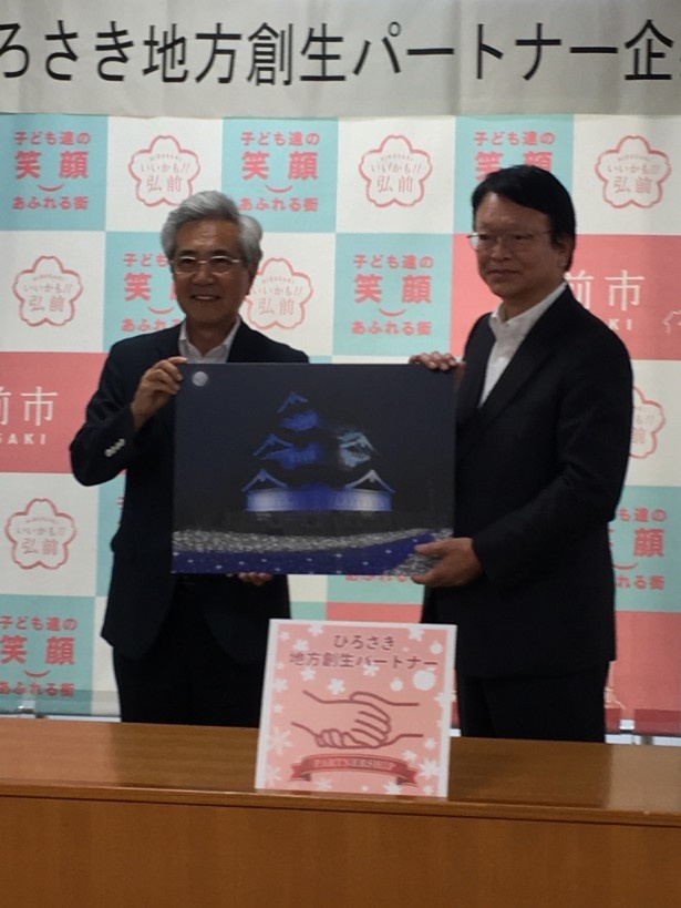 【写真を見る】「青海に揺らぐ幻想天守」は、葛西憲之弘前市長(写真左)も期待を寄せる新たな観光資源だ