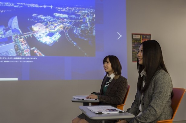 ウォーカープラス「夜景時間」に掲載された夜景スポットの写真を見ながら夜景の魅力を学ぶ高柳(写真左)と古畑