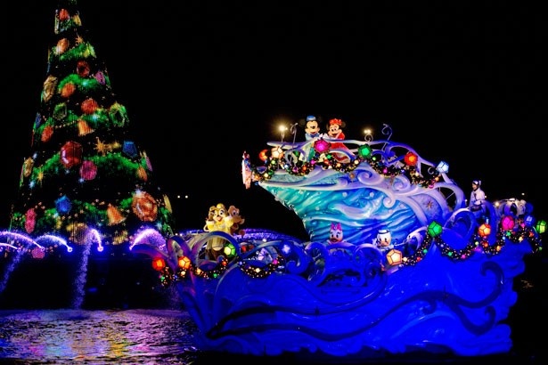 ハーバーの中央で輝く大きなクリスマスツリーと、15周年のデコレーションが施された船に乗るディズニーの仲間たち