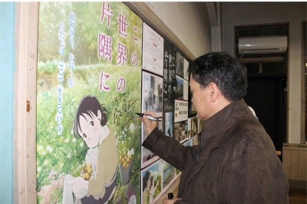 【写真を見る】立誠シネマを訪れてポスターにサインする片渕須直監督